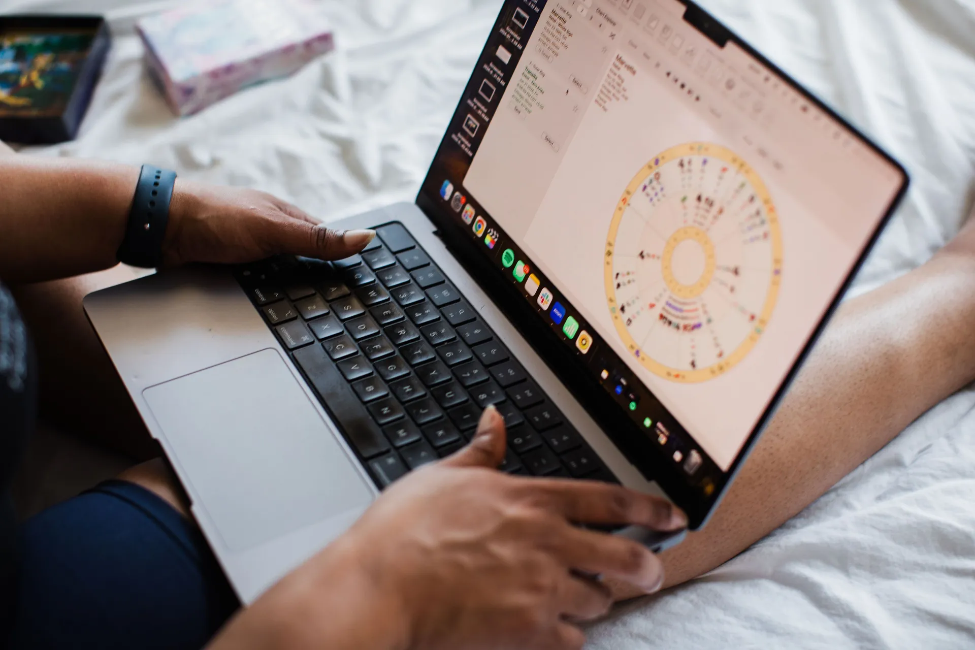 A person using a laptop to study a colorful astrology chart