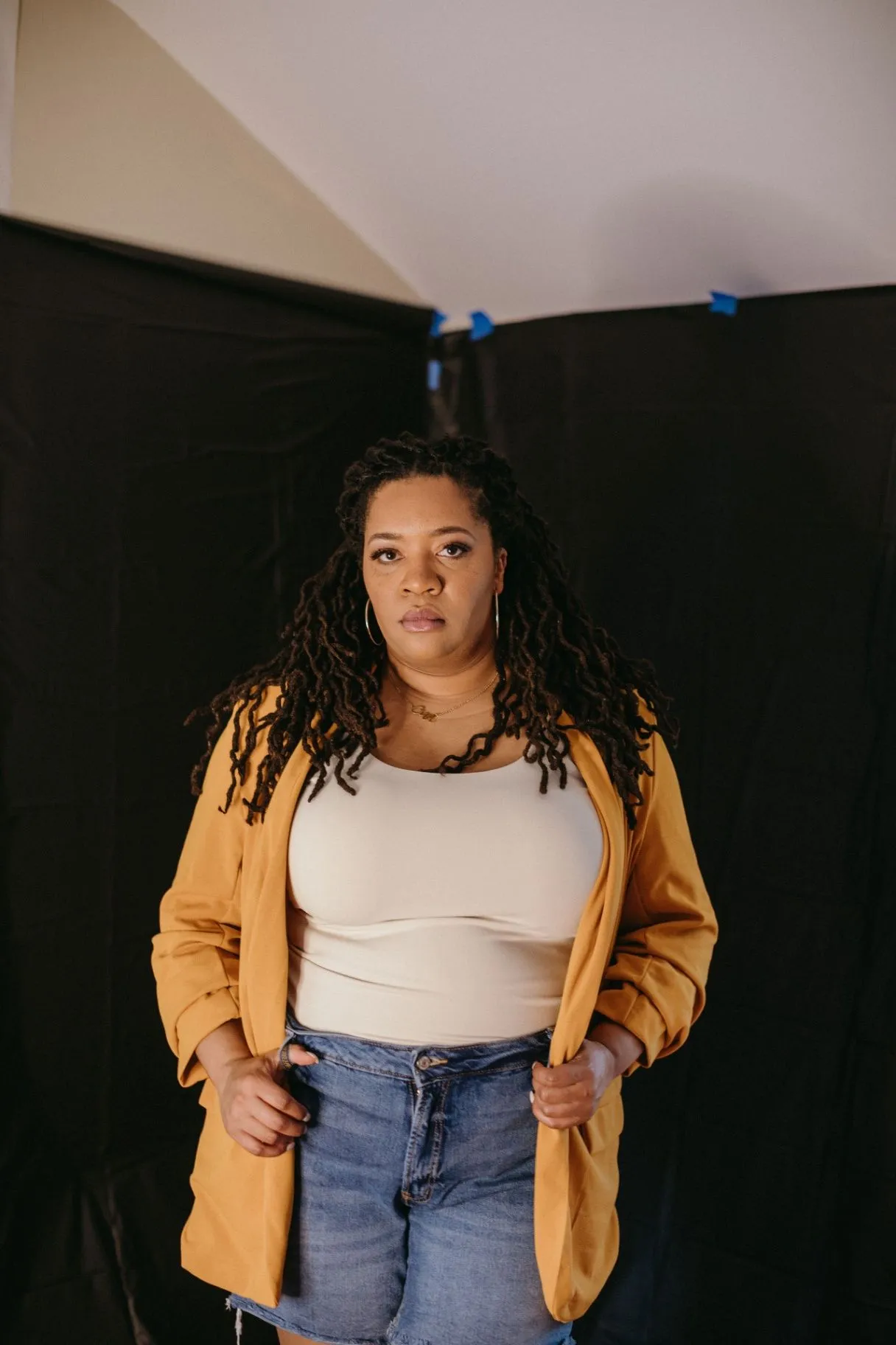 Dr. Marvette Lacy standing in a studio portrait wearing a golden jacket against a dark backdrop